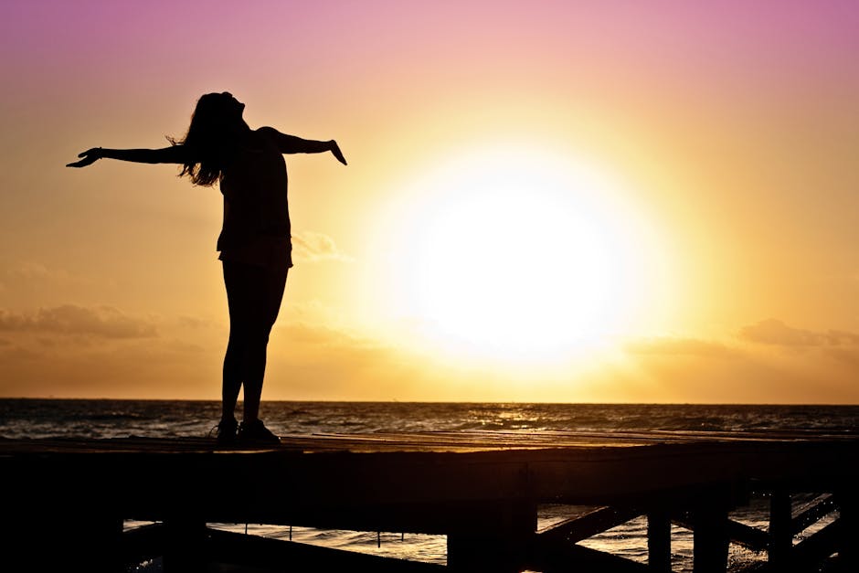 A joyful silhouette of a woman standing on a dock at sunset, embracing the freedom of nature.